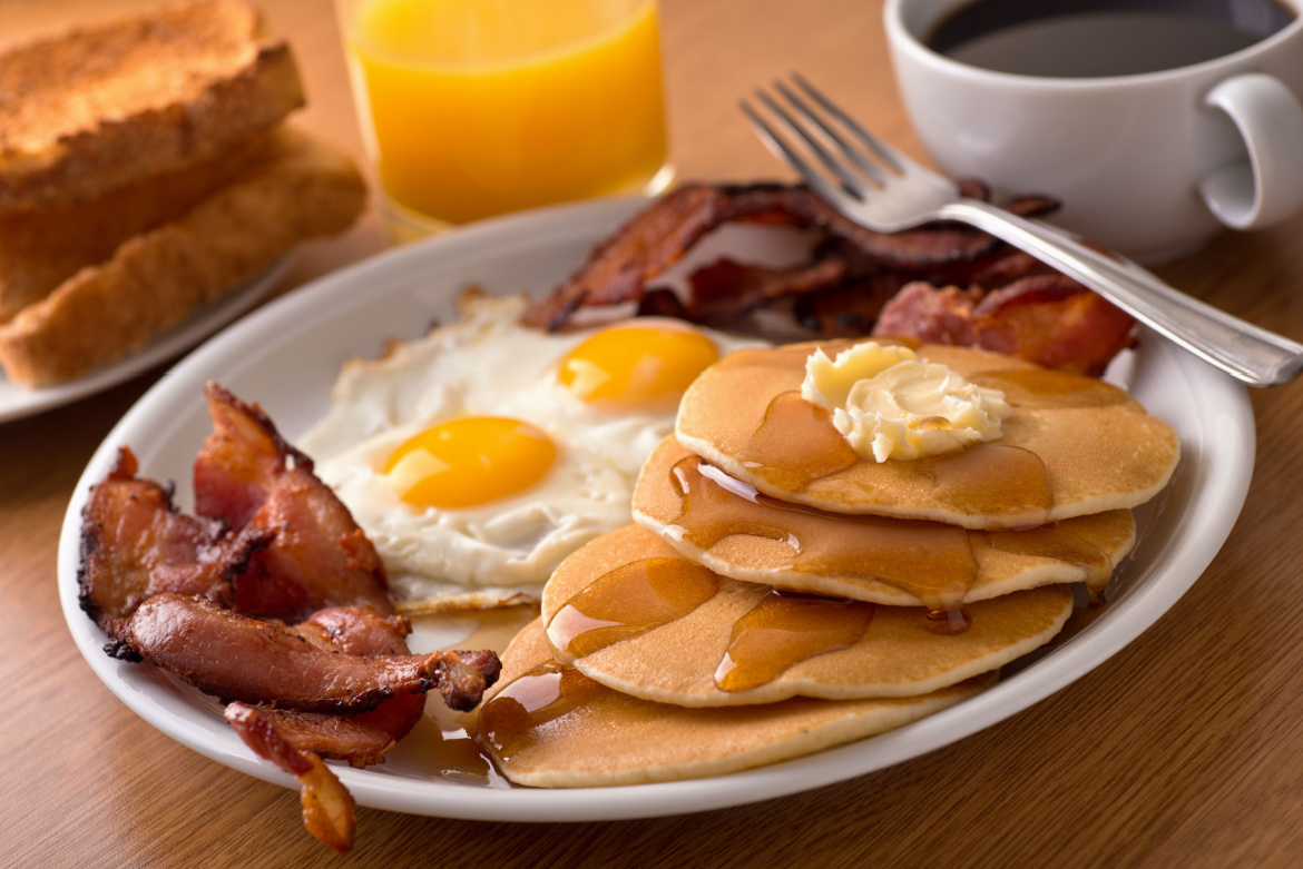 A delicious plate of pancakes, eggs and bacon